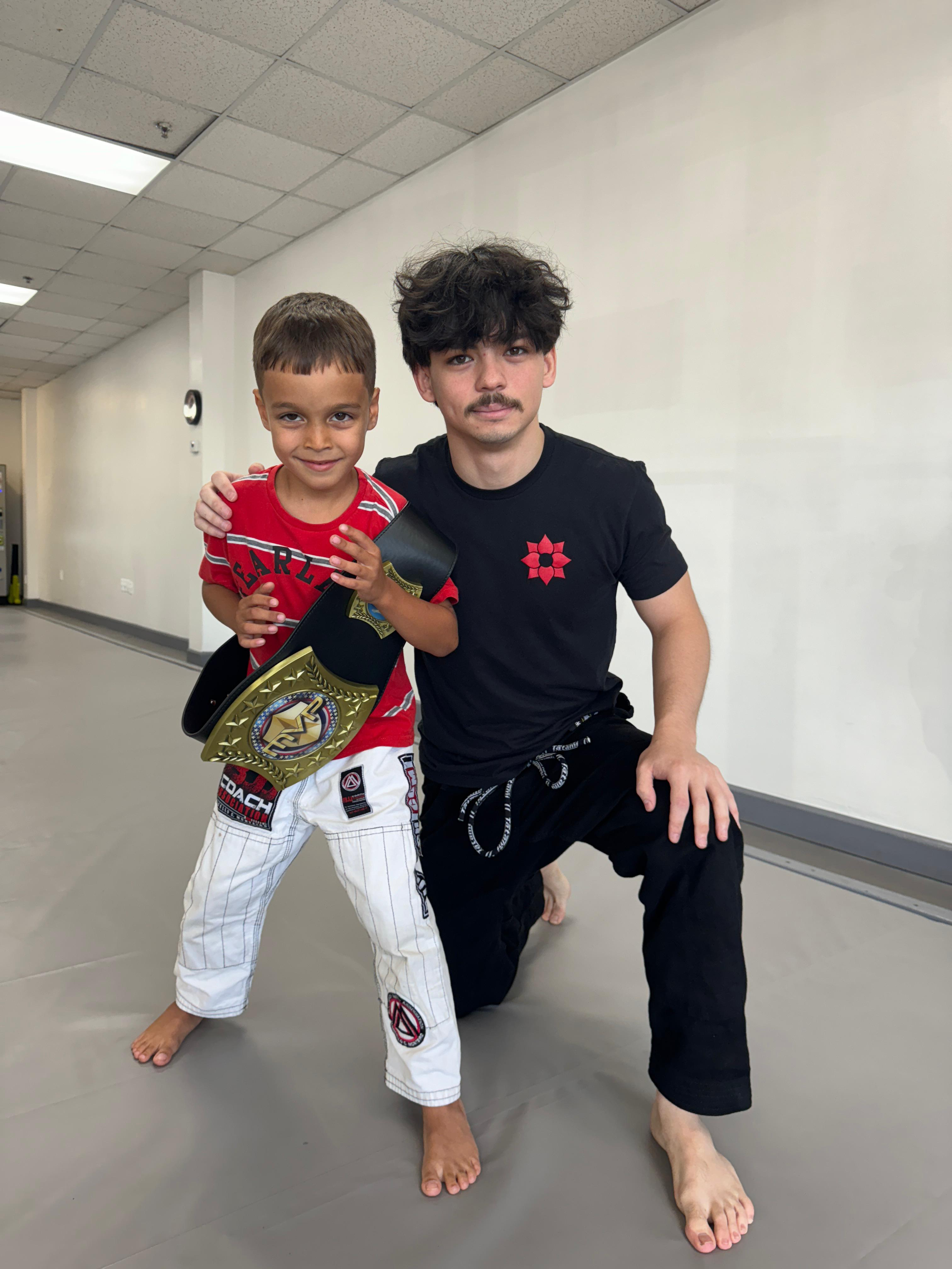 Luis with young student holding championship belt